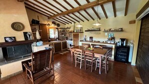 A spacious kitchen with wooden beams, a dining area with chairs, and a fireplace. - Villa and Annex House with Pool   InBorgo (MONTECASTRILLI)