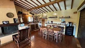 A spacious kitchen with wooden beams, a dining area with chairs, and a fireplace. - Villa and Annex House with Pool   InBorgo (MONTECASTRILLI)