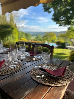 An outdoor dining table with empty wine glasses and cutlery, set on a wooden deck with a scenic view. - Villa and Annex House with Pool   InBorgo (MONTECASTRILLI)
