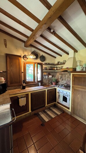 A kitchen with wooden beams, a stove, and various kitchen utensils. - Magical Umbrian Villa and Guest House with Pool (MONTECASTRILLI)