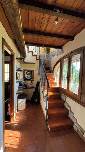 A wooden staircase leading to a second floor with a stone wall and a view of greenery outside. - Magical Umbrian Villa and Guest House with Pool (MONTECASTRILLI)