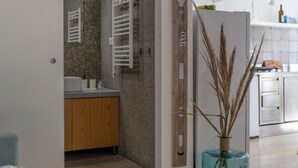 A modern bathroom with a tiled backsplash, a wooden vanity, a white towel rack, and a decorative vase with dried plants. - Dream Loft Roma 100 - Goelba (Capoliveri)