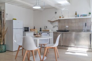 Eine moderne Küche mit weißen Geräten, ein Essbereich mit weißen Stühlen und einer gemusterten Spritzschutzleiste.