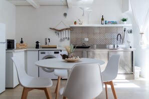 Eine moderne Küche mit Essbereich, einschließlich einer Waschmaschine, einem Spülbecken und einer Arbeitsplatte mit diversen Gegenständen.