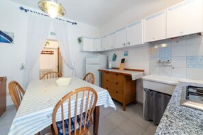 A compact kitchen with a dining table, chairs, a refrigerator, and a sink. - Le Cote di Seccheto - Goelba (Campo nell'Elba)