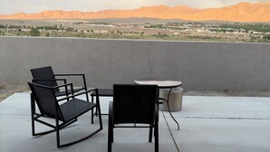 Ein Balkon mit zwei Stühlen und einem Tisch mit Blick auf eine Stadtlandschaft und Berge.