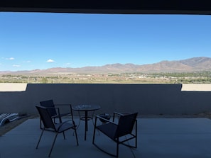 A patio with chairs and a table, overlooking a mountainous landscape.