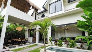 A modern house with a pool, outdoor seating, and lush greenery. - Orfeas Villas 1 - Luxury 2BR Canggu Private Pool, Rooftop Lounge (Kabupaten Badung)
