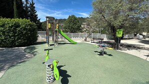 A playground with a slide, climbing structures, and a scooter.