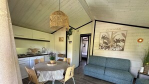 A compact living space with a dining table, chairs, a sofa, and a kitchen area.