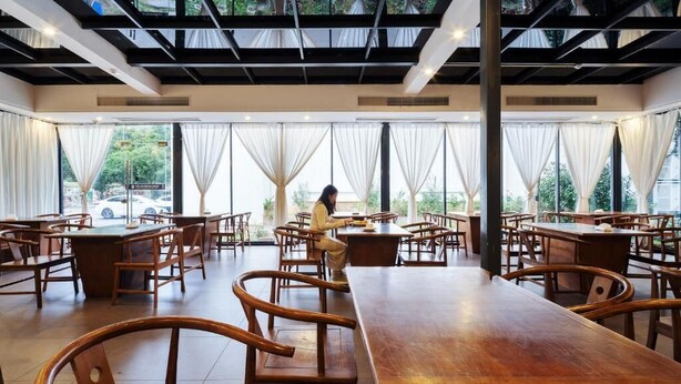 A spacious restaurant with high ceilings, large windows, and wooden furniture. - Tianchong Yunhai Courtyard Hotel (Zhangjiajie)