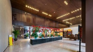 A spacious lobby with a wooden ceiling, a red decorative structure, and a seating area with potted plants. - Tianchong Yunhai Courtyard Hotel (Zhangjiajie)