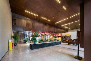 A spacious lobby with a wooden ceiling, a red decorative structure, and a seating area with potted plants. - Tianchong Yunhai Courtyard Hotel (Zhangjiajie)