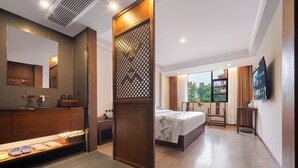 A hotel room with a bed, a desk, a TV, a bathroom with a mirror, and a window with a view. - Tianchong Yunhai Courtyard Hotel (Zhangjiajie)