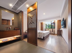 A hotel room with a bed, a desk, a TV, a bathroom with a mirror, and a window with a view. - Tianchong Yunhai Courtyard Hotel (Zhangjiajie)