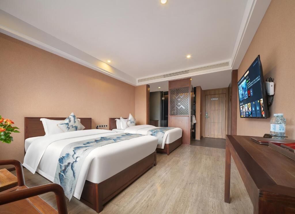 A hotel room with a large bed, a desk, a TV, and a door leading to a bathroom.