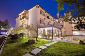 Um edifício de dois andares com varanda, entrada de vidro e um gramado bem cuidado.