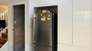 A kitchen with a stainless steel refrigerator, white cabinets, and a checkered mat at the entrance.