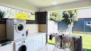 A laundry area with two washing machines, a drying rack, and a tiled floor.