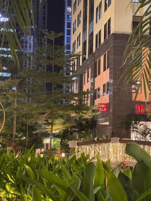 Un hotel con fachada moderna, un letrero que dice 'UNIOLO', rodeado de exuberante follaje y otros edificios al fondo.