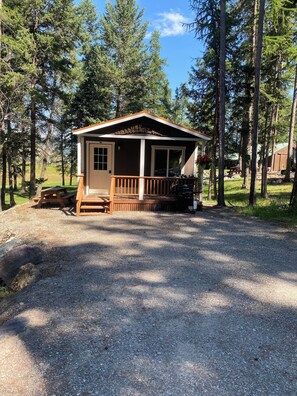 A small cabin with a porch, surrounded by trees.