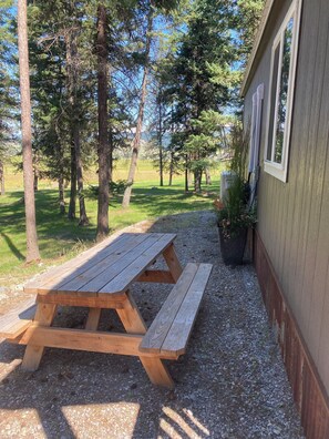 A picnic table in a wooded area with a building in the background.
