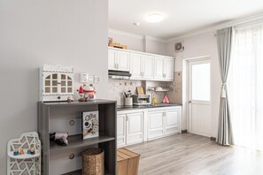 Eine moderne Küche mit weißen Schränken, einem Einbauofen und einem Fenster mit Vorhängen.