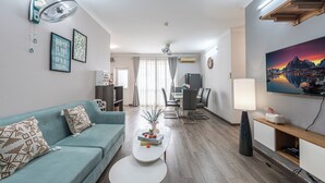 En moderne stue med sofa, sofabord, spiseplads og tv.