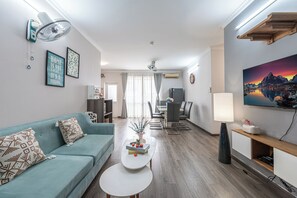 Ein modernes Wohnzimmer mit Sofa, Couchtisch, Essbereich und Fernseher.