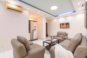 Ein modernes Wohnzimmer mit beigen Sofas, einem Couchtisch und einem Gemälde an der Wand.