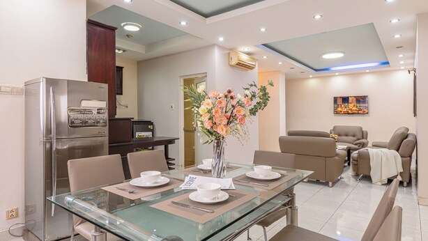 Ein modernes Wohnzimmer mit einem Glastisch, beigefarbenen Sofas und einer dekorativen Vase.