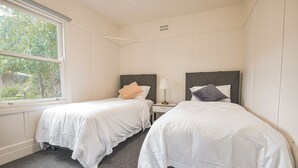 Ein Hotelzimmer mit zwei Betten, einem Fenster und einem Nachttisch mit Lampe.