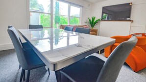 Ein Konferenzraum mit Glastisch, Stühlen, einer Couch und einem Fernseher an der Wand.