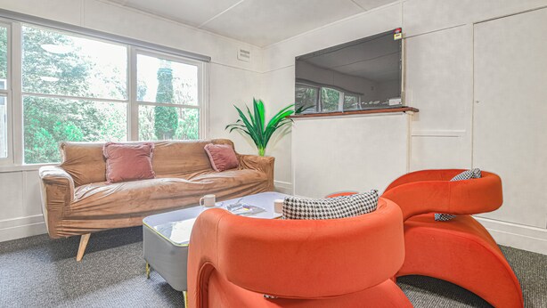 Ein Zimmer mit einem braunen Ledersofa, einem kleinen Tisch mit einer Zeitschrift und zwei orangefarbenen Sesseln.
