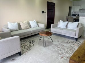 Ein Wohnzimmer mit zwei Sofas, einem Couchtisch und einem gemusterten Teppich.