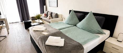 A modern hotel room with a large bed, bedside tables, a desk, and a window with curtains.