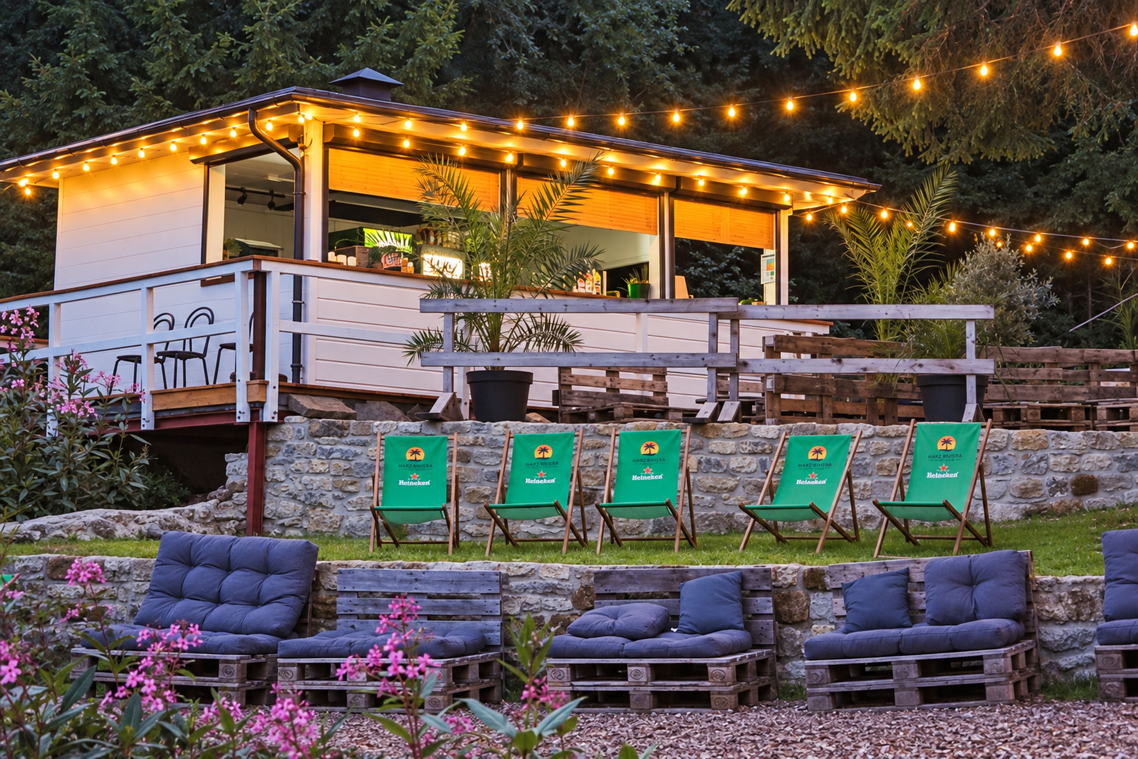 A building with a balcony, string lights, and outdoor seating with green cushions.