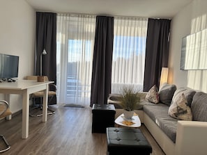 Ein modernes Wohnzimmer mit einer Couch, einem Couchtisch, einem Fernseher und einem Essbereich mit Tisch und Stühlen.