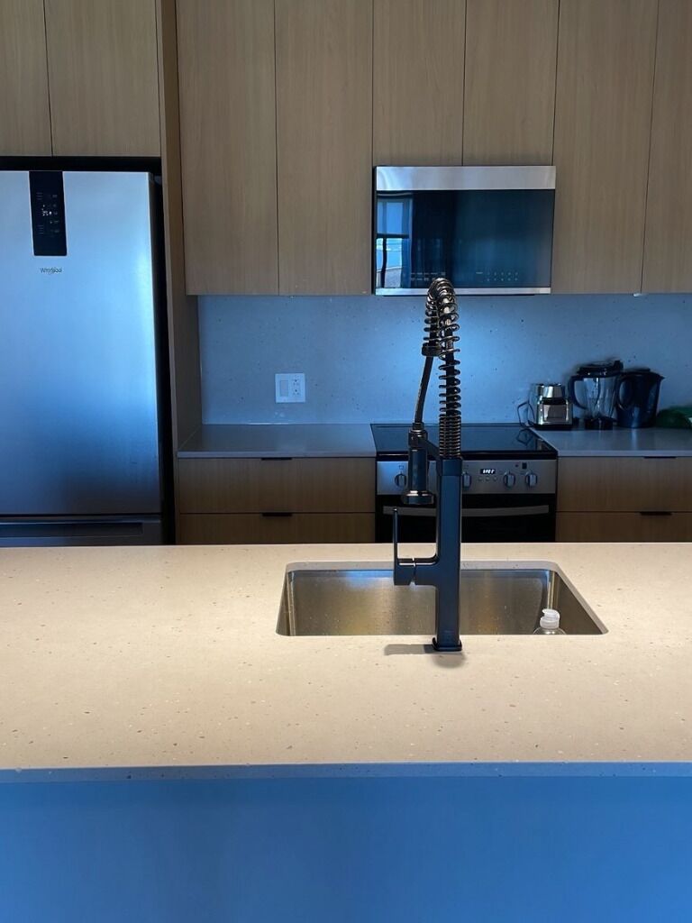 Una cucina con lavello in acciaio inossidabile, fornello e pensili in legno.