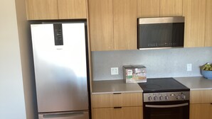 Una cocina con armarios de madera, un refrigerador de acero inoxidable, un microondas y un horno.