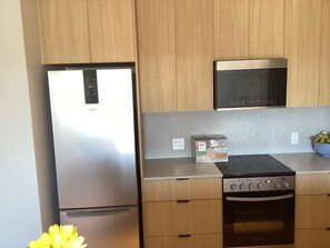 Una cocina con armarios de madera, un refrigerador de acero inoxidable, un microondas y un horno.