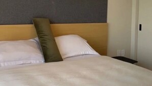 Habitación de hotel con una cama, cabecero, una puerta y una pared con textura.