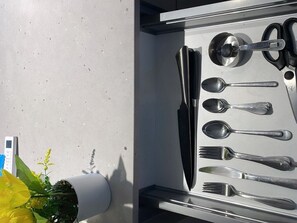 Un cajón con cubiertos, un cuchillo y una cuchara.