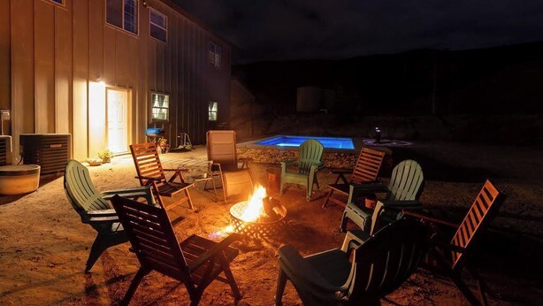 Patio esterno con sedie e un braciere, una piscina e un edificio con finestre.