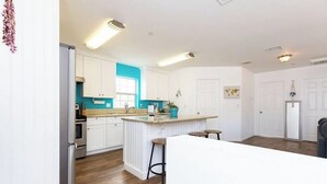 Una cucina moderna con mobili bianchi, una parete di colore blu e un'isola centrale con sgabelli.