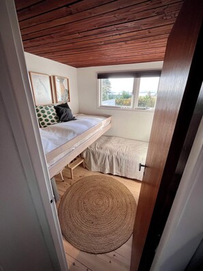 A bedroom with a bunk bed, a window with a view, and a woven rug on the floor. - 2 bedroom accommodation in Millinge (Millinge)