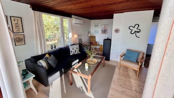 Un salon comprenant un canapé, une table basse, un fauteuil, une lampe et un mur décoré d’un motif représentant un trèfle à quatre feuilles.
