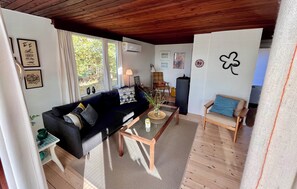 Ein Wohnzimmer mit einer Couch, einem Couchtisch, einem Sessel, einer Lampe und einer Wand mit Klee-Dekoration.