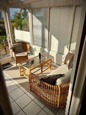 A sunlit room with wicker furniture, a glass coffee table, and a view of the outdoors. - 2 bedroom accommodation in Millinge (Millinge)