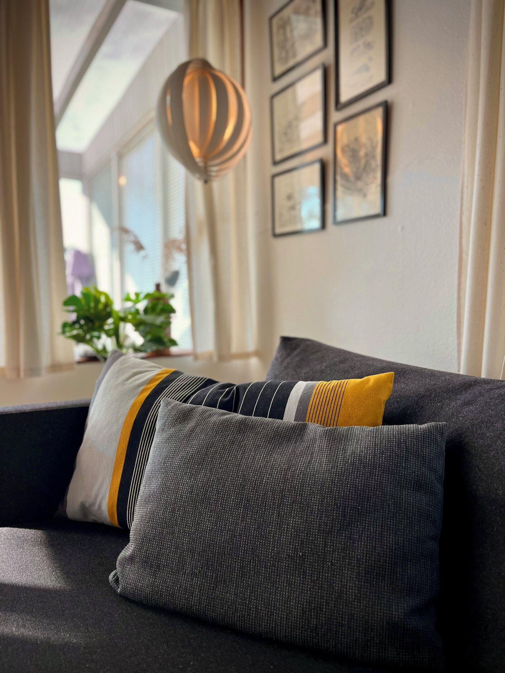 Ein modernes Wohnzimmer mit Sofa, Kissen und einer Pendelleuchte.